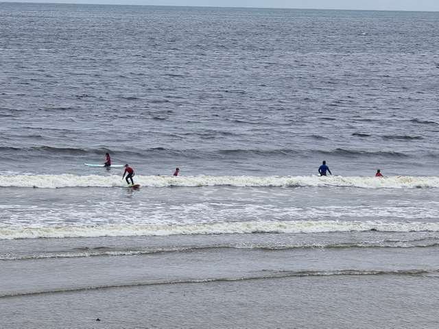 Beginner surfer riding a knee high wave in front of the shop
